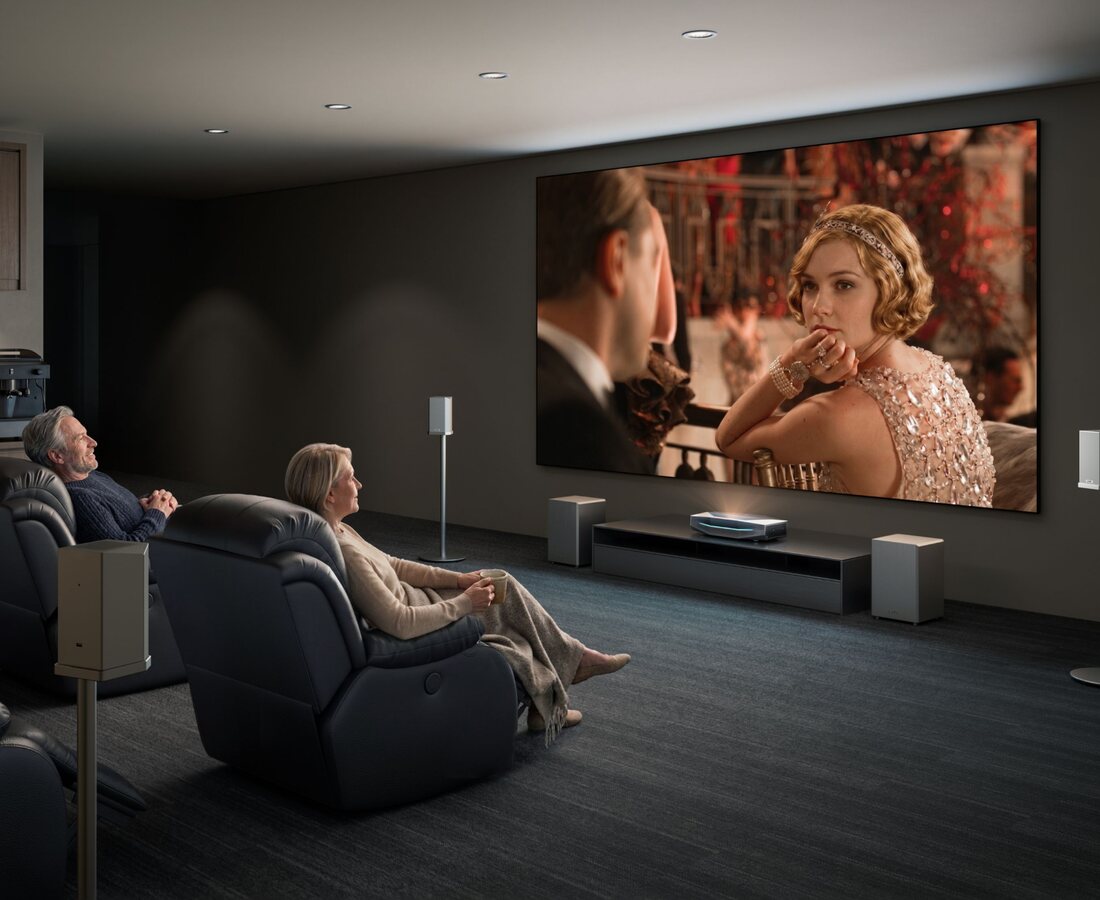 Proyector láser AWOL Vision Aetherion Max sobre el mueble de una sala de cine en casa con sillones reclinables